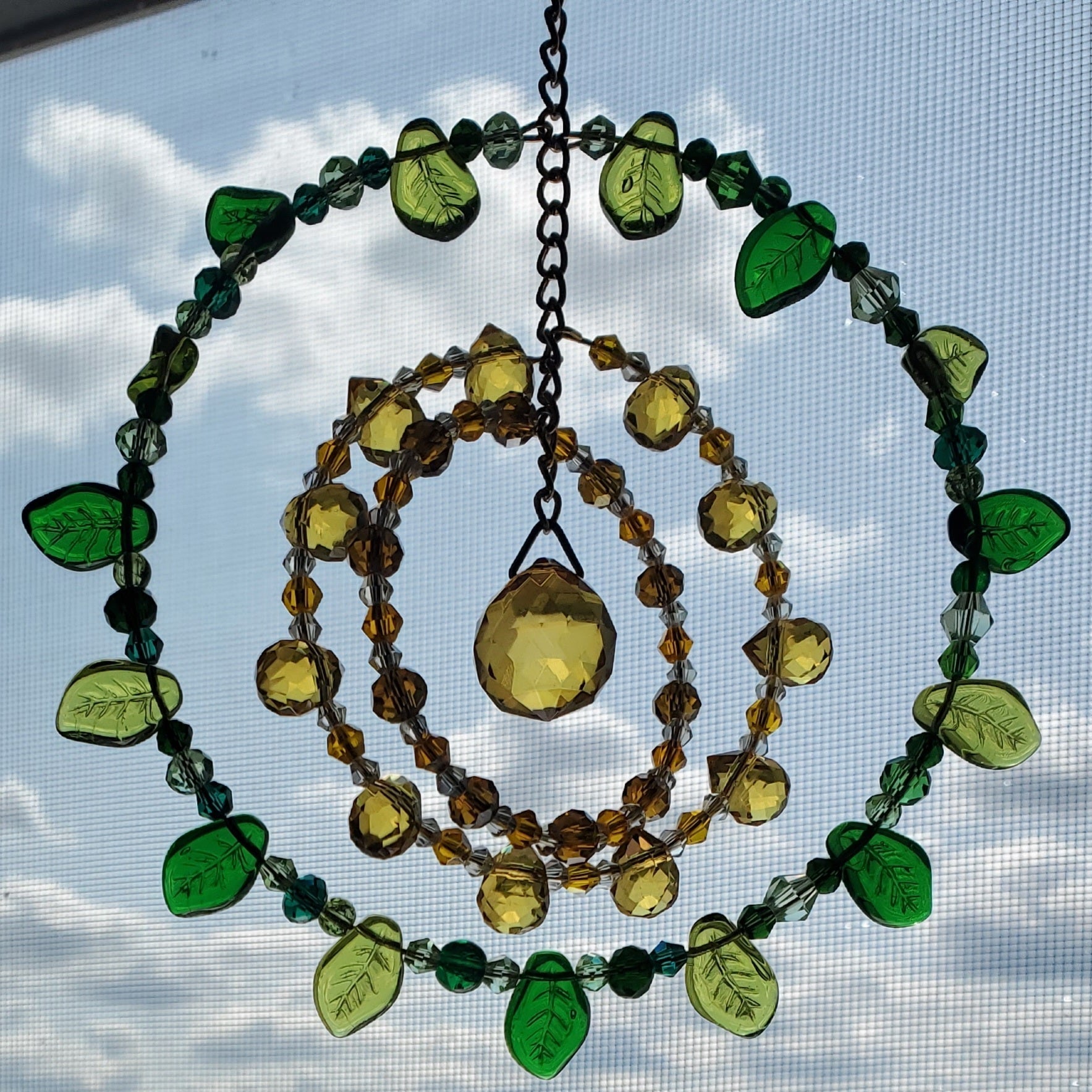 Handcrafted sunflower mandala crystal suncatcher with yellow, amber, green beads and topaz prism reflecting sunlight