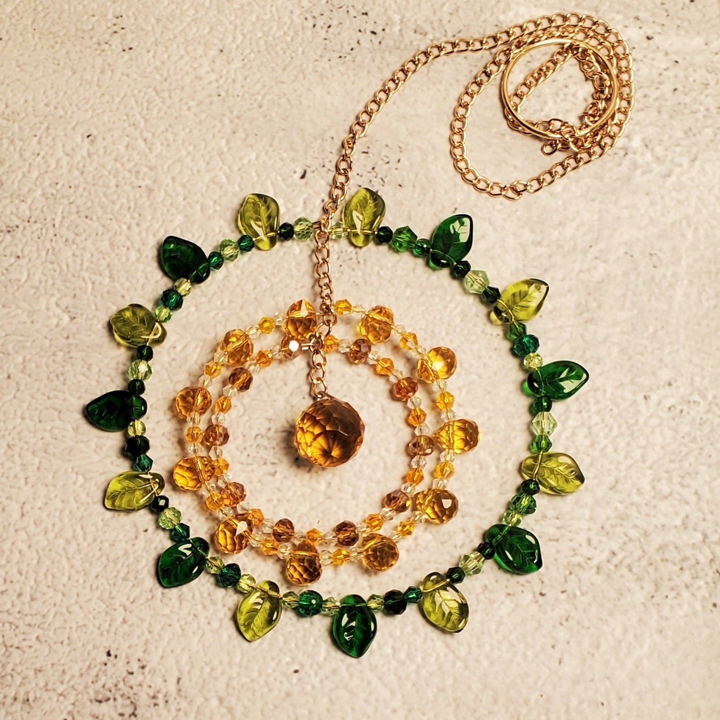 Handcrafted crystal suncatcher with sunflower mandala design featuring yellow, amber, green crystals and a topaz prism centerpiece