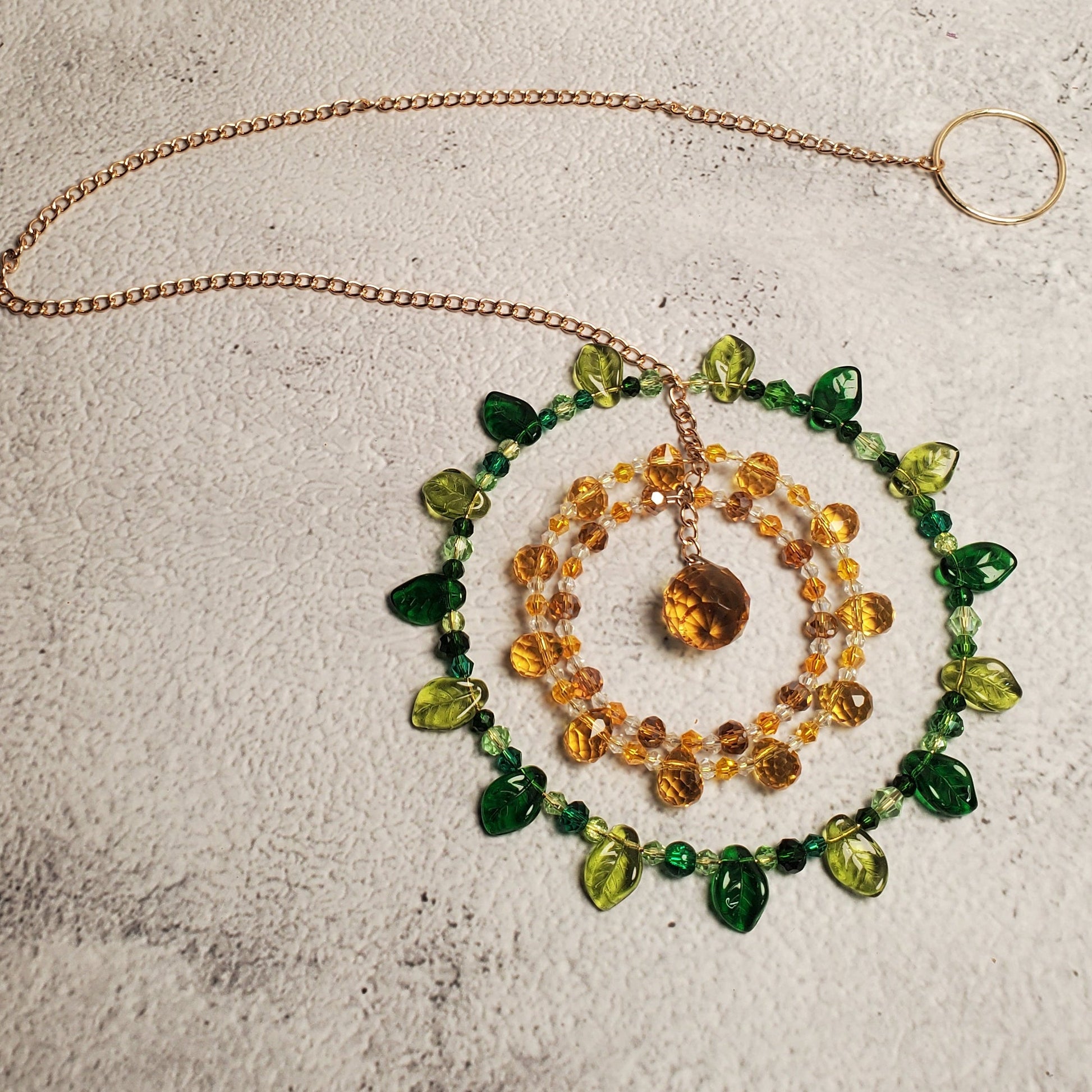 Handcrafted sunflower mandala crystal suncatcher with yellow, amber, green beads and topaz prism reflecting sunlight