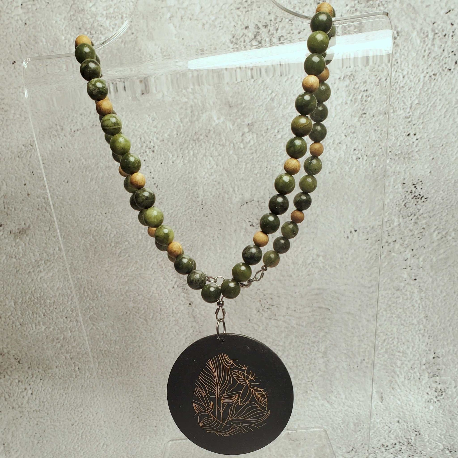 Handcrafted gemstone necklace featuring genuine Chinese jade beads and a wood pendant with floral etching