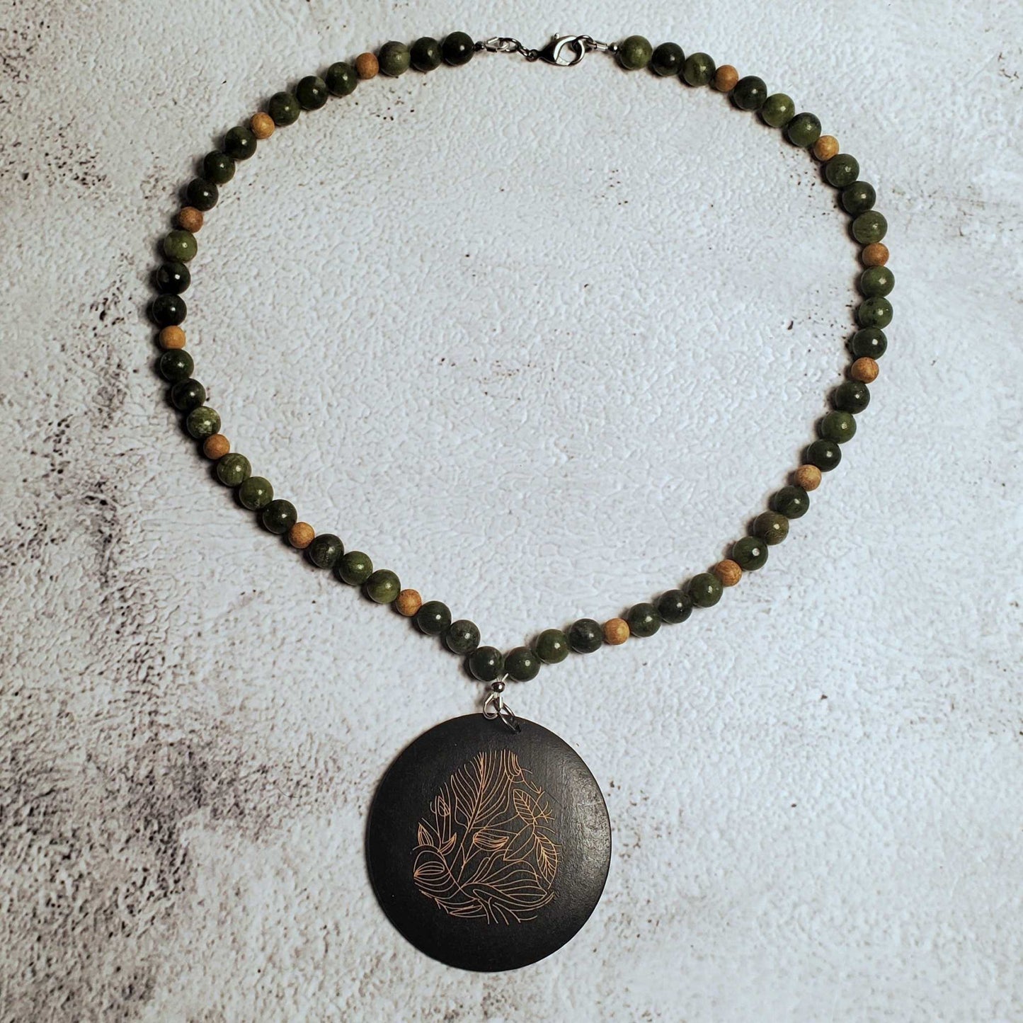 Handcrafted gemstone necklace featuring genuine Chinese jade and a carved wood pendant with floral design