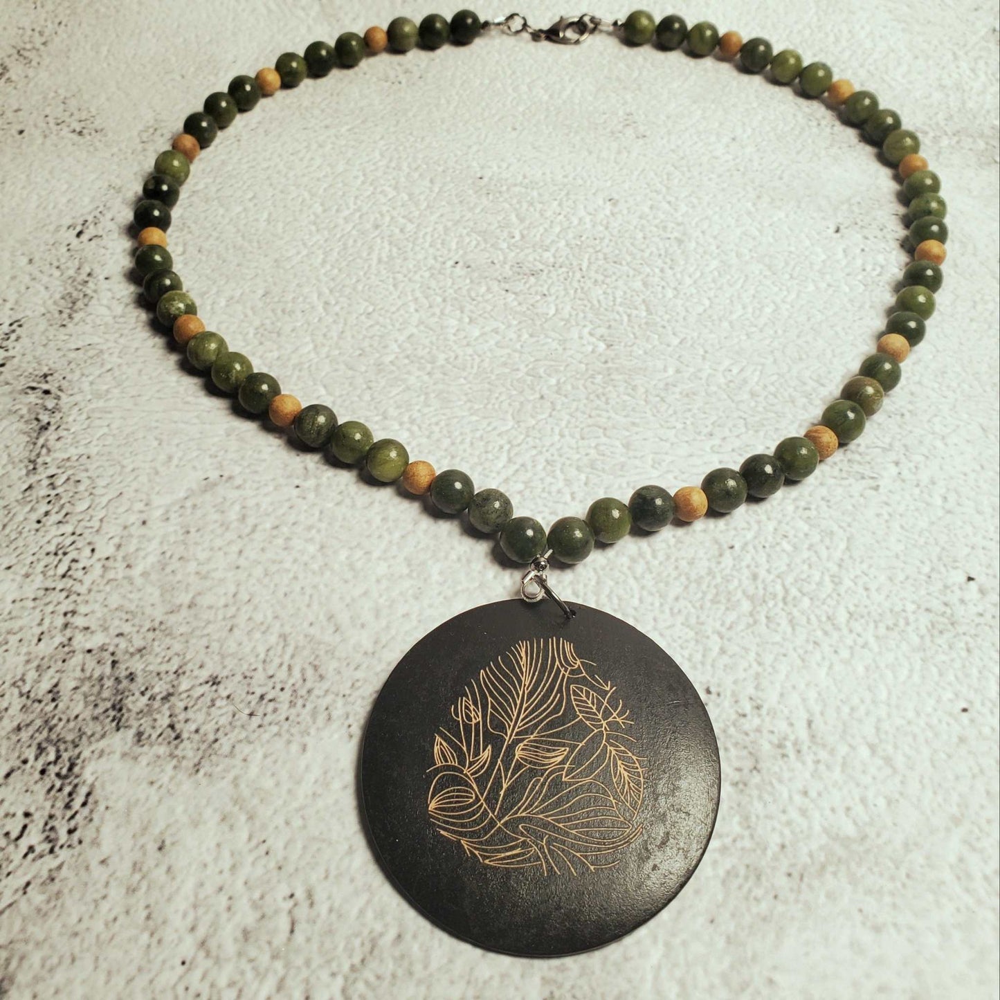 Handcrafted gemstone necklace featuring genuine Chinese jade beads and a natural wood pendant with floral design