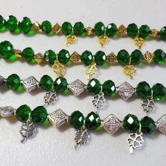 Shamrock bracelet with green glass beads and Celtic knot spacers in pewter and brass charms, featuring a lobster claw clasp.
