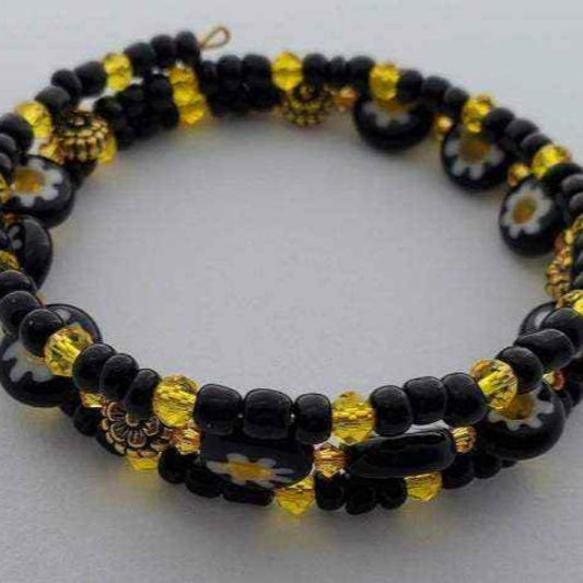 Adjustable floral bracelet featuring black and white daisy millefiori beads with yellow crystal and glass accents
